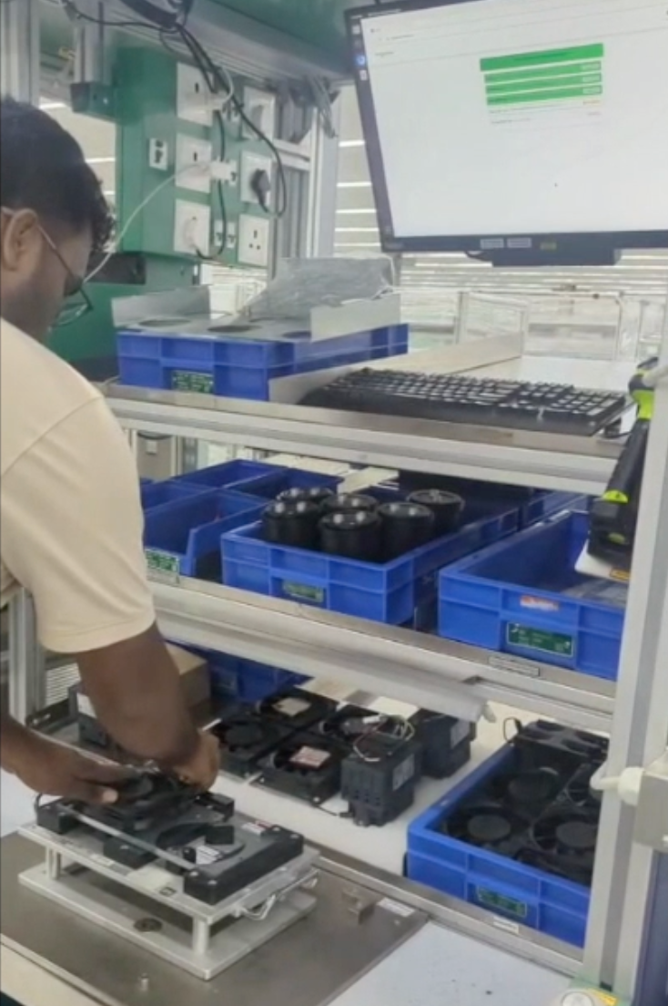 Operator placing a sub-assembly on the fixture with the live dashboard showing PASS steps